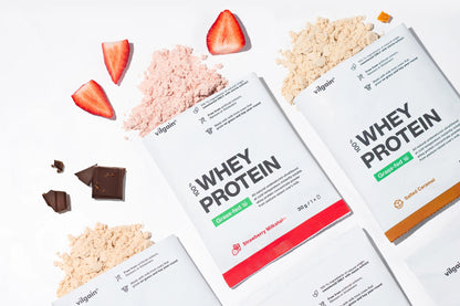 Grass-Fed Whey Protein packages with flavors like chocolate, strawberry, and vanilla on a white background.